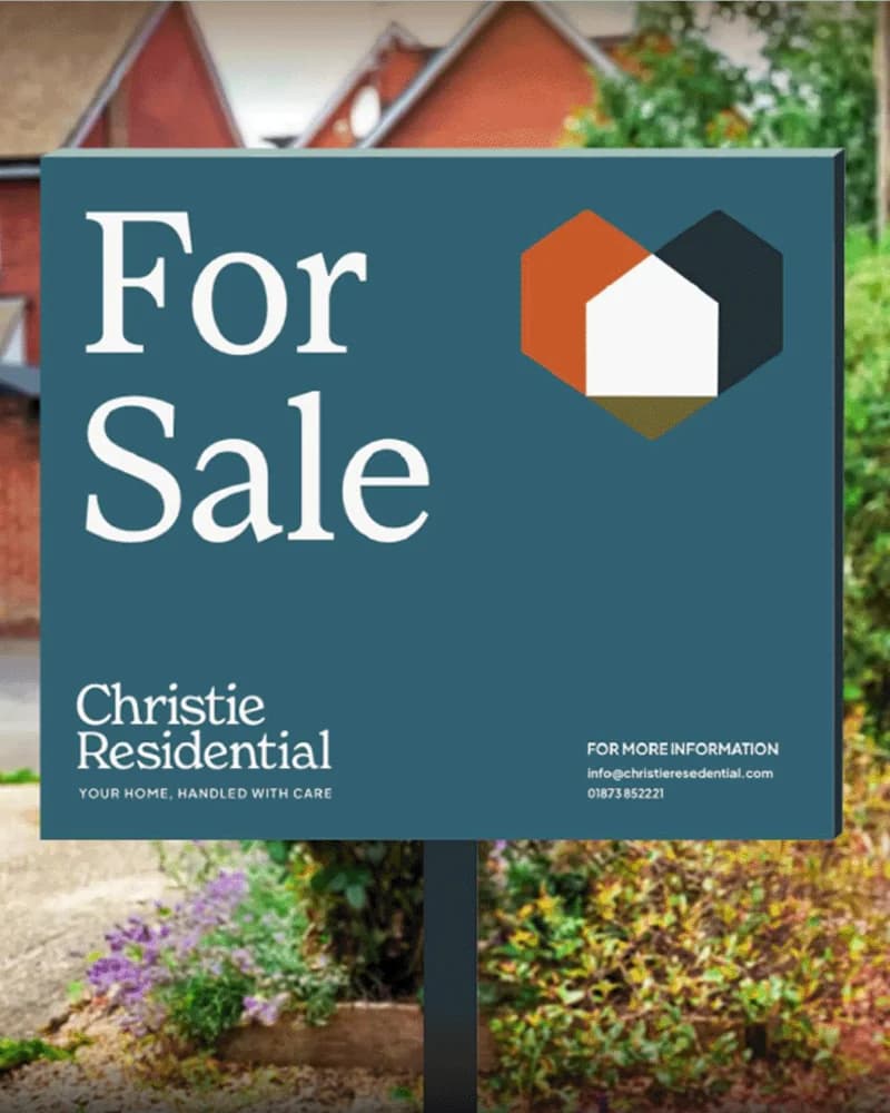 A Christie Residential For Sale board standing in a front garden, the hexagon house mark in orange, teal and olive above the line 'Your home, handled with care'.