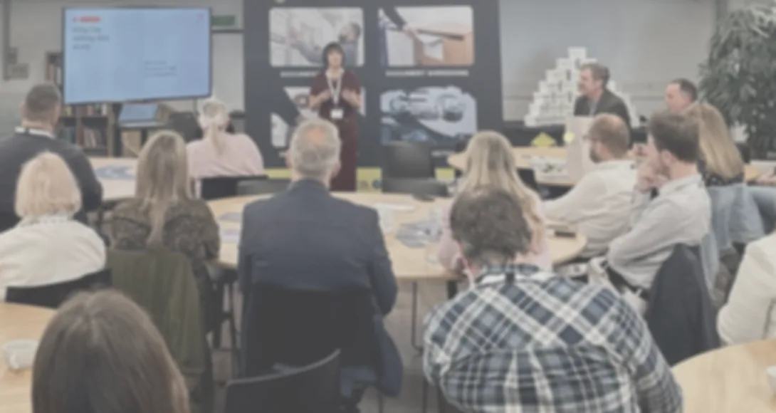 Jess Morgan presenting to a room of business owners seated around tables.