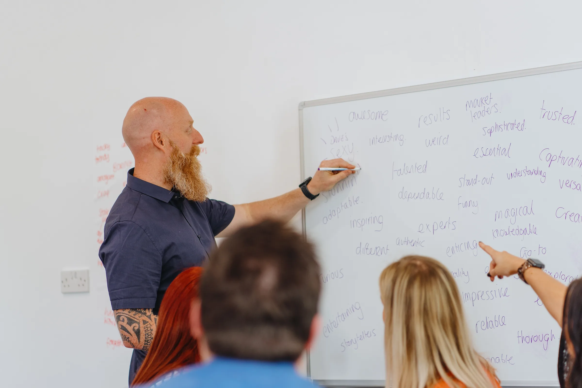 A whiteboard filled with words a leadership team used to describe their business, being added to during a session.